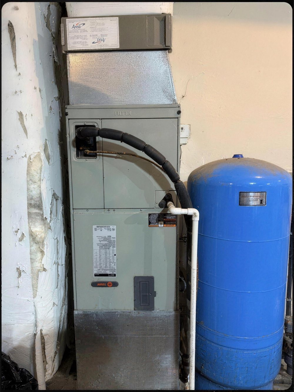 Before: the old air handler beside a blue pressure tank